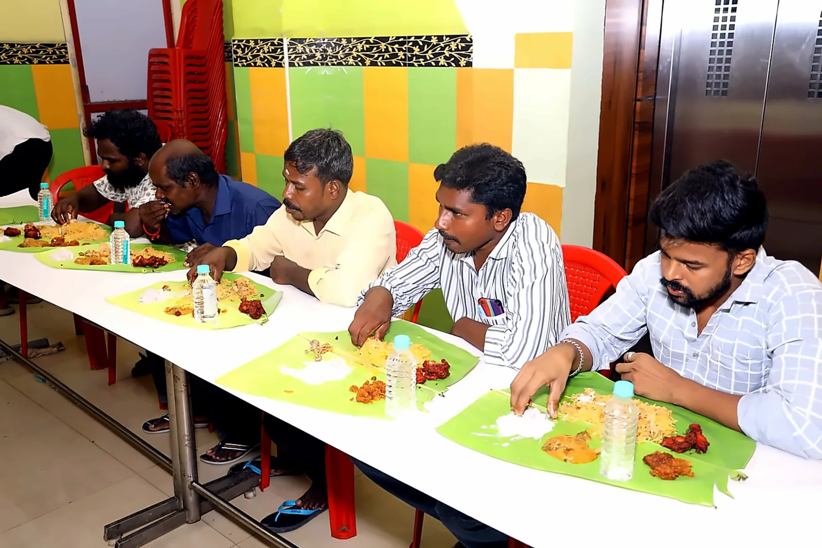 Row of guests seated for an Ambur style biryani and fried chicken banana-leaf feast in Chennai