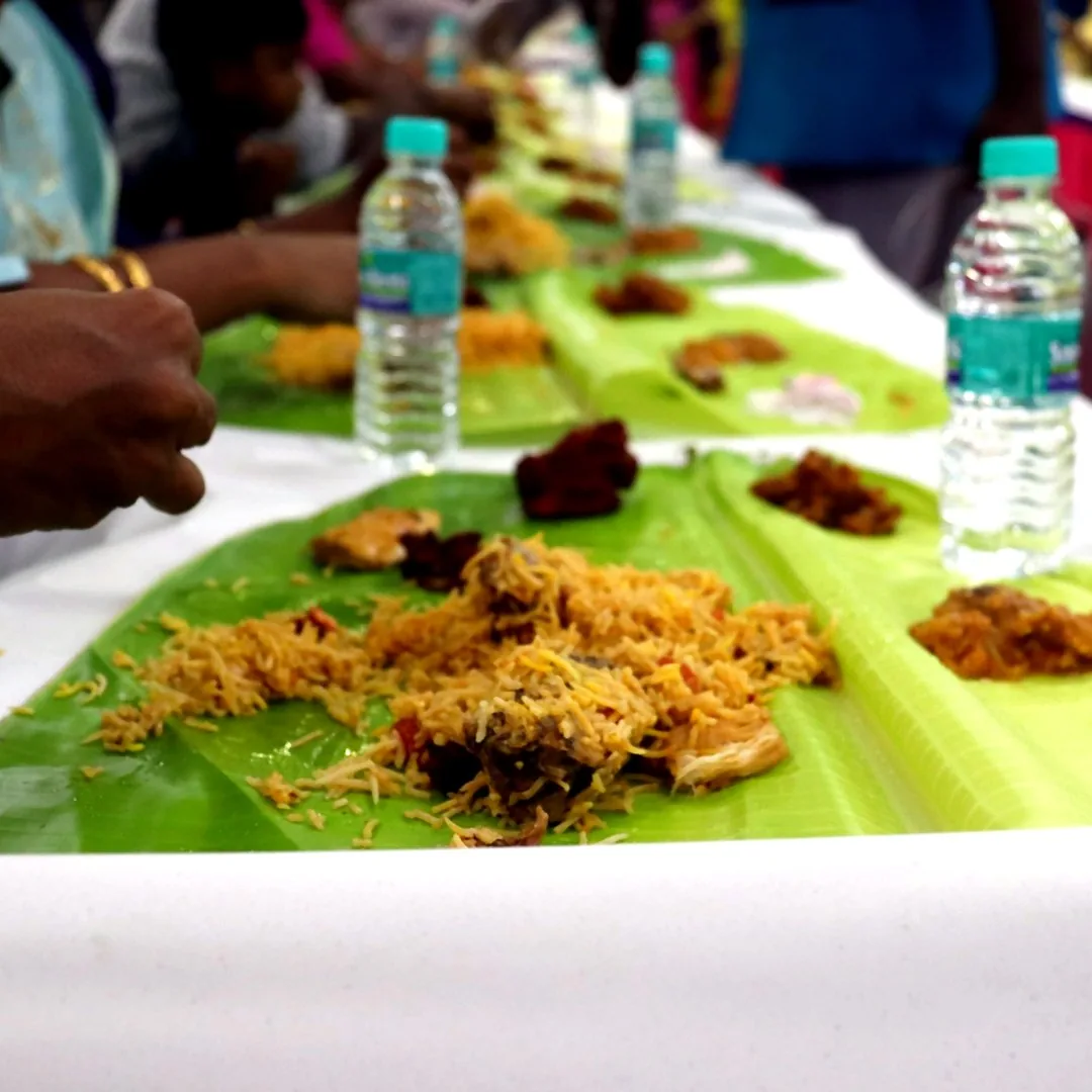 Authentic Chennai style chicken biryani served on a banana leaf with brinjal gravy, raita and boiled egg