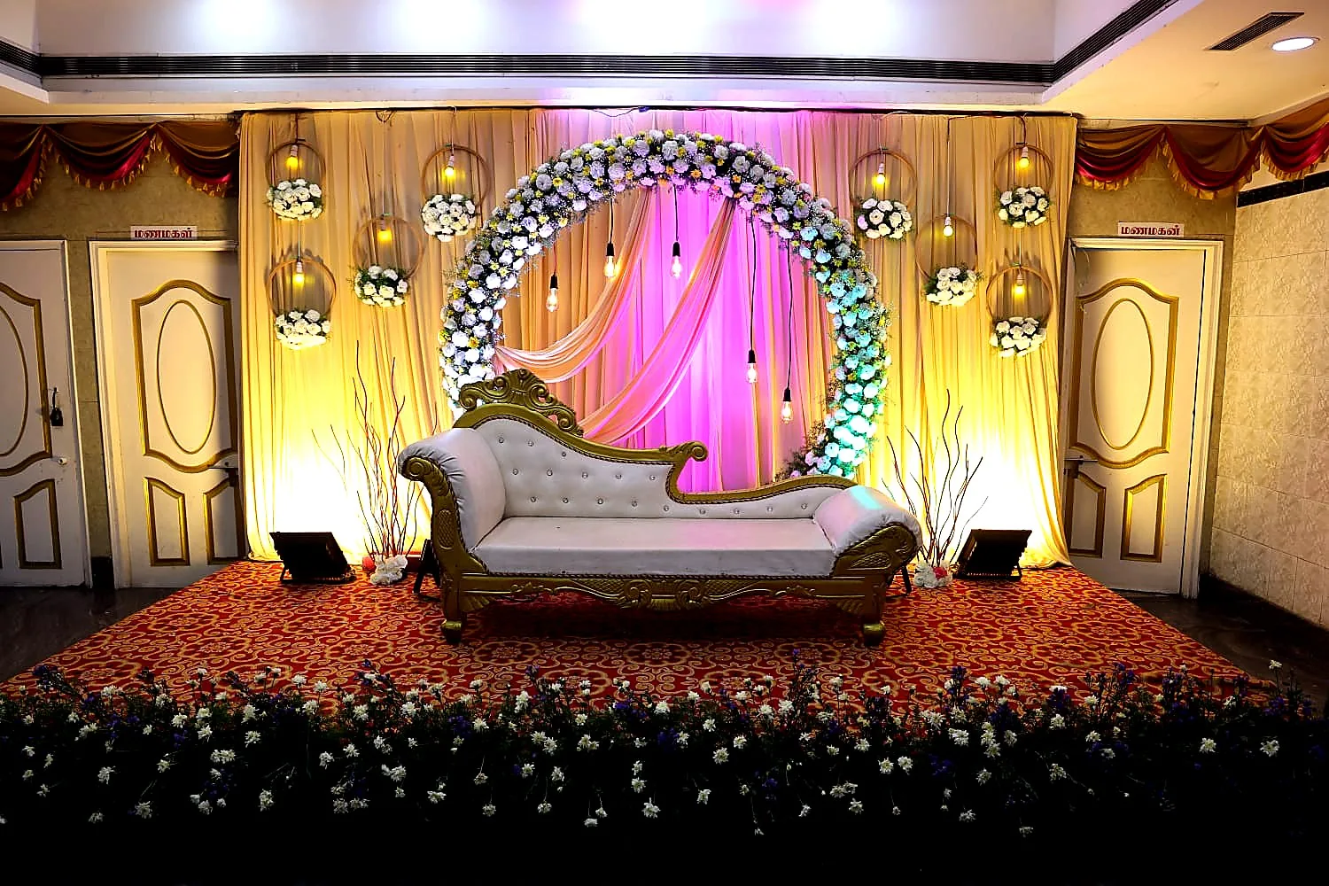 Pastel floral ring mandap wedding stage with draped backdrop and ambient lighting at a Chennai wedding hall